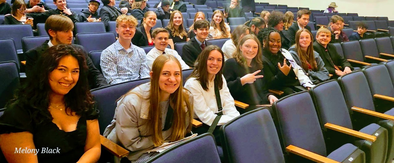 Students seated in auditorium, smiling